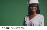 Confident female engineer in protective helmet smiling against green background. Стоковое AI-видео, аниматор Владимир Федоров / Фотобанк Лори