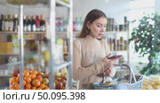 Visiting store, girl scrolling phone screen and looking for something in showcase. Стоковое видео, видеограф Яков Филимонов / Фотобанк Лори