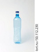 Empty transparent plastic bottle with blue cap on a light gray background, copy space. Mock up.. Blue transparent bottle for water on a light background. Mock up. Стоковое фото, агентство Ingram Publishing / Фотобанк Лори