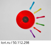 Creative pattern with multicolored plastic forks and red retro vinyl record on a light gray background. Place for text. Process of fertilized egg by sperms concept.. Colorful plastic forks around red vinyl record on a light gray background. Стоковое фото, агентство Ingram Publishing / Фотобанк Лори