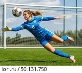 A female soccer player in a blue uniform is diving to catch a soccer ball. Стоковое AI-изображение, AI-художник Ярославский Максим / Фотобанк Лори