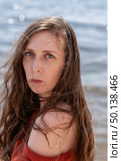 A young woman with long hair and blue eyes, wearing a terracotta sweater, looks sadly into the camera, against the backdrop of the sea. Стоковое фото, фотограф Кашапова Эльвира / Фотобанк Лори
