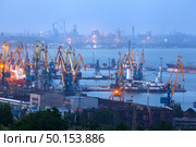 Sea commercial port at night against working steel factory in Mariupol, Ukraine. Industrial view. Cargo freight ship with working cranes bridge in sea port at twilight. Cargo port, logistic. Стоковое фото, агентство Ingram Publishing / Фотобанк Лори