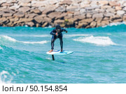 A middle aged man doing some foil surfing or hydrofoil surfing in the sea on a bright sunny day. Стоковое фото, агентство Ingram Publishing / Фотобанк Лори
