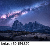 Milky Way over beautiful mauntains at night. Autumn landscape with mountains, purple sky with stars and bright milky way, buildings, trees, high rocks. Alpe di Siusi in Dolomites, Italy. Space. Стоковое фото, агентство Ingram Publishing / Фотобанк Лори