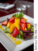 Colorful salad with strawberries and peaches on a bed of mixed greens, beautifully arranged in a white bowl, highlighting fresh ingredients and healthy dining experience. Стоковое AI-изображение, AI-художник Ирина Ручушкина / Фотобанк Лори
