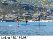Stand up paddleboarding on lake. Watersport on lake. Tourist outdoor activity at Lagoa Comprida, Serra da Estrela National Park in Portugal. Стоковое фото, агентство Ingram Publishing / Фотобанк Лори
