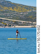 Stand up paddleboarding on lake. Watersport on lake. Tourist outdoor activity at Lagoa Comprida, Serra da Estrela National Park in Portugal. Стоковое фото, агентство Ingram Publishing / Фотобанк Лори