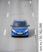 Zenith view of blue Hyundai Solaris car racing on highway road. Hyundai Verna automobile in motion, aerial top down view. Редакционное фото, фотограф Константин Григорьев / Фотобанк Лори