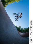 Biker jump high from jump box ramp performing table top trick. Стоковое фото, агентство Ingram Publishing / Фотобанк Лори