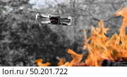 Flying drone Quadcopter with camera pointed at viewer outdoor in a bright fire in the foreground spurts of flame. Стоковое фото, фотограф Camptoloma / Фотобанк Лори
