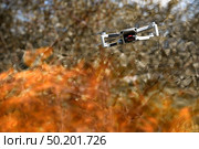 Flying drone Quadcopter with camera pointed at viewer outdoor in a fire in the foreground spurts of flame background of trees. Стоковое фото, фотограф Camptoloma / Фотобанк Лори