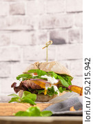 Healthy vegan burger with fresh vegetables and yogurt sauce on rustic kitchen counter top. Стоковое фото, агентство Ingram Publishing / Фотобанк Лори