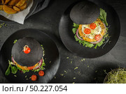 Tasty grilled veggie burgers with chickpeas and vegetables on black bread on dark wooden countertop. Стоковое фото, агентство Ingram Publishing / Фотобанк Лори