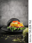 Tasty grilled veggie burgers with chickpeas and vegetables on black bread on dark wooden countertop. Стоковое фото, агентство Ingram Publishing / Фотобанк Лори