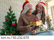 beautiful asian girl give surprise christmas gift to her boyfriend in Christmas holiday season greeting. Стоковое фото, агентство Ingram Publishing / Фотобанк Лори