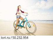 An attractive young woman riding her bicycle on the beach. Стоковое фото, агентство Ingram Publishing / Фотобанк Лори