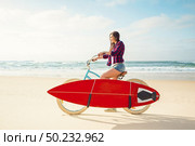 Surfer young woman riding her bicycle on the beach. Стоковое фото, агентство Ingram Publishing / Фотобанк Лори