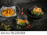 Tasty grilled veggie burgers with chickpeas and vegetables on black bread on dark wooden countertop. Стоковое фото, агентство Ingram Publishing / Фотобанк Лори