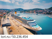 Aerial view of cruise ship in harbor. Top view of beautiful large ships and boats at sunny day. Landscape with harbour, city, buildings, mountains, blue sea. Luxury cruise. Floating liner in port. Стоковое фото, агентство Ingram Publishing / Фотобанк Лори