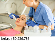 Female cosmetologist performing soften skin keratin and deep clear skin dirt use vibrating shovel leather knife for young female. Стоковое фото, фотограф Яков Филимонов / Фотобанк Лори