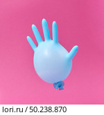 Flying blue rubber surgical glove as a balloon on a hot pink background with copy space. Minimalism concept.. Blue latex glove balloon on a hot pink background. Стоковое фото, агентство Ingram Publishing / Фотобанк Лори