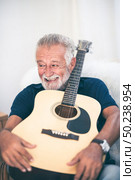 Grandfather hugged the guitar and smiled. Стоковое фото, агентство Ingram Publishing / Фотобанк Лори