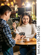 Asian customer using credit card with contactless nfs technology to pay a waiter for coffee purchase at table in cafe. Стоковое фото, агентство Ingram Publishing / Фотобанк Лори