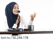 Young Muslim woman do face cosmetic with mirror and makeup brush on white background taken in studio. Using for Fashion and beauty concept. Стоковое фото, агентство Ingram Publishing / Фотобанк Лори