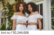 Two women standing side by side in front of a house, looking at the camera. Стоковое AI-изображение, AI-художник Данила Большаков / Фотобанк Лори