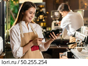 Asian Barista make payment with customer credit card using  EMV chip technology for coffee purchase at a cafe bar. Стоковое фото, агентство Ingram Publishing / Фотобанк Лори