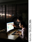 Young adult asian businessman dicuss with collegue about work late at night in their office with desktop computer. Using as hard working and working late concept. Стоковое фото, агентство Ingram Publishing / Фотобанк Лори