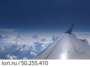 View from the window of airplane on an aircraft wing on a background of blue cloudy sky in a sunny day. Place for your text. Travel and transportation concept.. Wing of aircraft on a background of clear blue sky. Стоковое фото, агентство Ingram Publishing / Фотобанк Лори