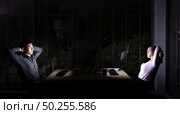 Young adult asian businessman and woman stretching while working late at night in their office with desktop computer and laptop. Using as hard working and working late concept. Стоковое фото, агентство Ingram Publishing / Фотобанк Лори