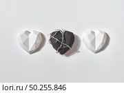 Three gypsum hearts on a light grey background with shadows and copy space. One of them is black and wrapped twisted wire. Valentine’s day greeting card.. Hearts set from plaster figures and one with wire. Стоковое фото, агентство Ingram Publishing / Фотобанк Лори
