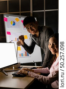 Young adult asian businessman and businesswoman work with analysis graph on white board late at night in their office with desktop computer. Using as hard working and working late concept. Стоковое фото, агентство Ingram Publishing / Фотобанк Лори