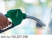 Man Handle pumping gasoline fuel nozzle to refuel. Vehicle fueling facility at petrol station. White car at gas station being filled with fuel. Transportation and ownership concept. Стоковое фото, агентство Ingram Publishing / Фотобанк Лори