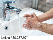 Man is washing hands with soap and hot water at home bathroom sink. Guy is cleaning hands. Hygiene for coronavirus outbreak prevention. Covid-19 pandemic protection by washing hands frequently. Стоковое фото, агентство Ingram Publishing / Фотобанк Лори