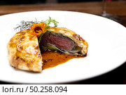 Roasted Beef Wellington with gravy brown savory sauce, international gourmet cuisine of stuff beef meat in baked bread puff. Unising for recipe menu pf food and drink industry.. roasted beef wellington. Стоковое фото, агентство Ingram Publishing / Фотобанк Лори