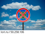 Prohibition sign with crossed out Coronavirus, Covid-19 molecule on the background of blue cloudy sky. Restriction of air communication between countries. Global calamity. Quarantine concept.. Forbbiden sign with crossed out Coronavirus. Стоковое фото, агентство Ingram Publishing / Фотобанк Лори