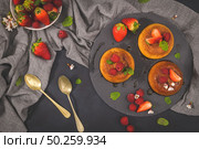 Caramel custard puddings on round slate on and dark kitchen countertop. Стоковое фото, агентство Ingram Publishing / Фотобанк Лори