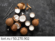 Coconut milk, whole and cracked coconuts on black background, top view. Стоковое фото, агентство Ingram Publishing / Фотобанк Лори