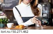 Asian Barista woman holding creadit card reader machine cashless payment for coffee purchase at cafe. Cashless preventing from coronavirus covid-19 Spreading and infection, Panoramic web banner crop. Стоковое фото, агентство Ingram Publishing / Фотобанк Лори