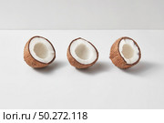 Fruits pattern from three exotic organic natural halves of ripe coconuts on a duotone light grey background with soft shadows, copy space. Vegetarian concept.. Set from three tropical natural halves of coconut on a light grey background. Стоковое фото, агентство Ingram Publishing / Фотобанк Лори