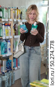 Girl housewife in household store examines goods, chooses mouthwash. Стоковое видео, видеограф Яков Филимонов / Фотобанк Лори