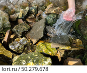 Природный источник. Родниковая вода течет на камни. Детская рука в воде. Natural source. Spring water flows onto the rocks. Child's hand in water. Стоковое фото, фотограф Александр Рыбалка / Фотобанк Лори