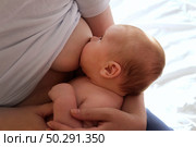 Mother breastfeeding baby at home. Mom nursing infant nurturing. Portrait of Child suckling milk from breast. Authentic shot of mother is breastfeeding her newborn baby. Close Up. Concept of maternity. Стоковое фото, фотограф Марина Демидюк / Фотобанк Лори