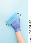 Medical antibacterial protective face mask on a woman’s hand in rubber glove on a light blue background from masks. Concept of prevention from respiratory sickness and viruses.. Medical mask on a woman’s hand in protective rubber glove. Top view. Стоковое фото, агентство Ingram Publishing / Фотобанк Лори