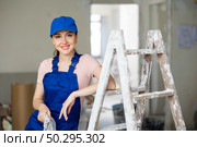 Portrait of positive builder woman in blue overalls next to stepladder. Стоковое фото, фотограф Яков Филимонов / Фотобанк Лори