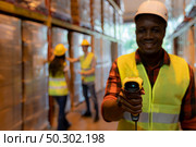 Close up of african black woman warehouse worker hold hand scanner to check inventory stock in distribution warehouse. Traceability FIFO LIFO inventory just in time and warehouse concept photo. Стоковое фото, агентство Ingram Publishing / Фотобанк Лори